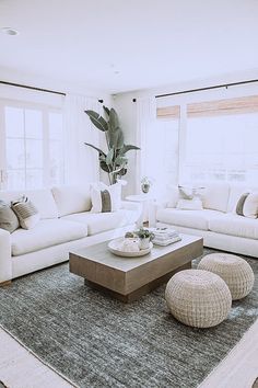 a living room filled with white furniture and large windows