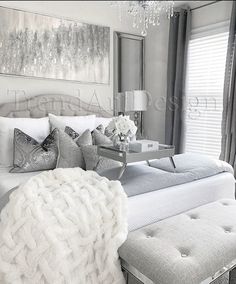 a white bed sitting next to a window with a chandelier hanging above it