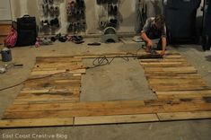 a person working on some wood in a room filled with shoes and other items that are being worked on