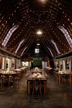 the inside of a barn with tables and chairs set up for an elegant dinner party