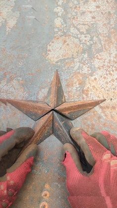 a person's feet in pink gloves standing next to a rusty star