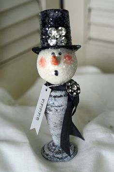 a small snowman with a black hat and bow tie on it's head