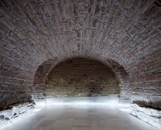 an empty brick tunnel with light coming in from the top and floor to the bottom