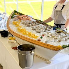 a man standing in front of a large platter filled with oysters and clams