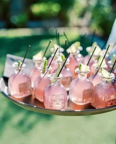 there are many small pink bottles with sticks sticking out of them on a silver tray