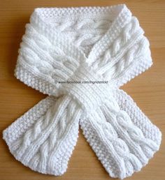 a white knitted scarf sitting on top of a wooden table