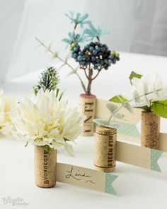 three wine corks with flowers in them sitting next to each other on a table