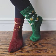 the legs of a woman wearing green socks with red and white designs on them, standing in front of a wall