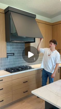 a man standing in a kitchen holding up a stove top oven over a countertop