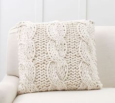 a white knitted pillow sitting on top of a couch