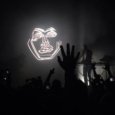 a person holding their hand up in front of a neon mask on a wall with the words hello