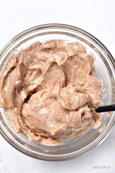 a bowl filled with peanut butter on top of a white counter next to a black spoon