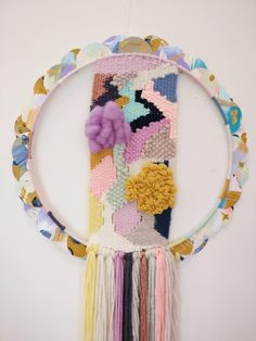 a multicolored wall hanging with flowers and tassels attached to the side