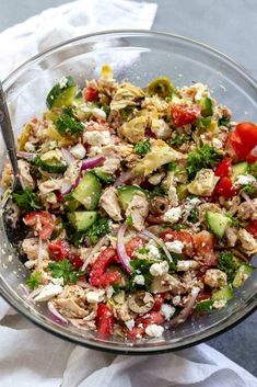 a glass bowl filled with salad on top of a white napkin next to a fork