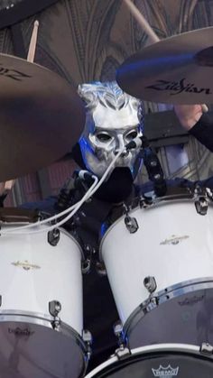 a man in silver mask playing drums on stage