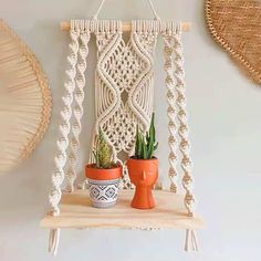 a macrame hanging from a wall with two potted plants on it and another planter in the foreground