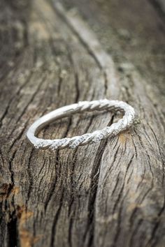 a white gold wedding band on top of a piece of wood