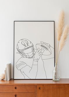 a black and white drawing of a football player holding a ball in front of a wooden dresser