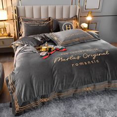 a bed with grey and gold comforters in a bedroom next to a night stand