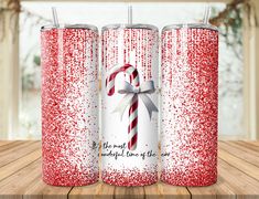 three red and white christmas tumblers with candy canes on the side, both decorated with glitter