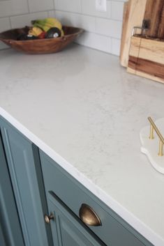 a white counter top in a kitchen next to a bowl of fruit