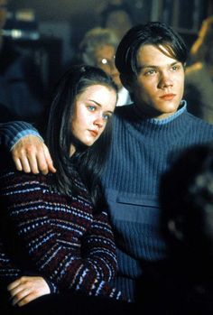 two people sitting next to each other in front of a crowd at a movie theater