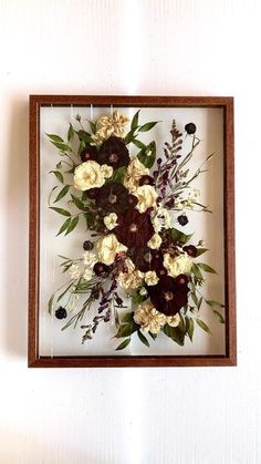 an arrangement of flowers in a wooden frame