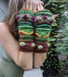 a woman holding her hands up to her face with crocheted mitts on