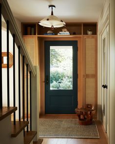 an entryway with a blue door and wooden steps leading up to the second floor