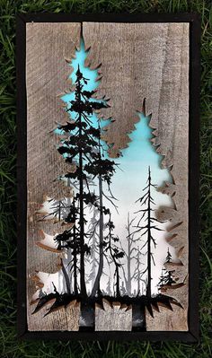 a piece of wood with trees cut out of it in the grass and some blue paint