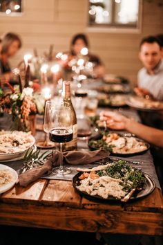 a group of people sitting at a table with plates of food and glasses of wine