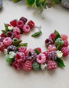 a bracelet made out of raspberries and flowers on top of a white table