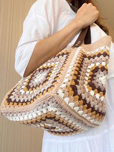 a woman is holding a crocheted bag in her right hand and wearing a white shirt