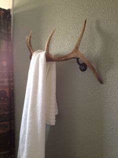 a deer antler head mounted to the side of a bathroom towel rack on a wall