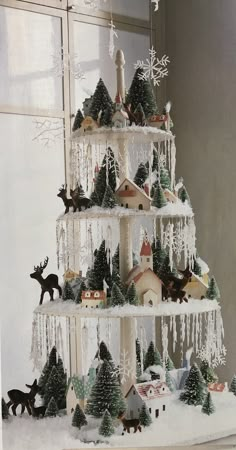 a christmas tree made out of fake snow and trees with animals on it, in front of a window