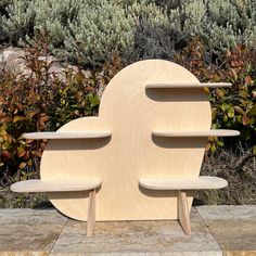 three wooden shelves sitting next to each other on top of a stone slab in front of bushes