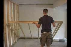 a man standing on top of a wooden floor in a room under construction with unfinished walls