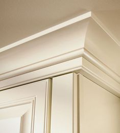 the corner of a kitchen cabinet with white paint and molding on it's edges