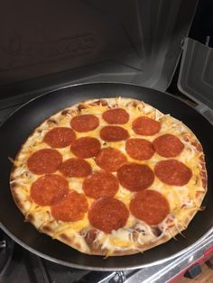 a pepperoni pizza sitting on top of a pan in the oven, ready to be cooked