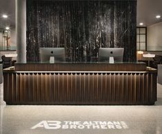 the front desk of an office with two computers on it's sides and a black wall behind it