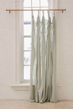 a window with curtains hanging in front of it and a curtain rod on the side