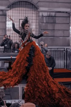 a woman in an orange dress standing on top of a car