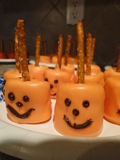 small pumpkins with faces on them are sitting on a white plate in the kitchen