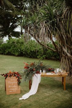 a wooden table topped with flowers and greenery next to a sign that says welcome