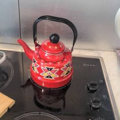 a red tea kettle sitting on top of a stove