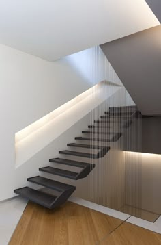 a modern staircase with glass railing and wood flooring