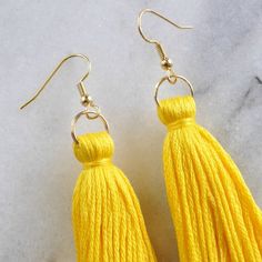 yellow tasseled earrings on marble surface