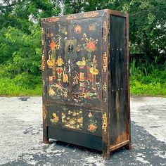 an old wooden cabinet with designs painted on it's sides in a parking lot