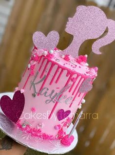 a pink birthday cake with hearts on top