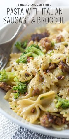 pasta with sausage and broccoli in a white bowl next to a fork on a table